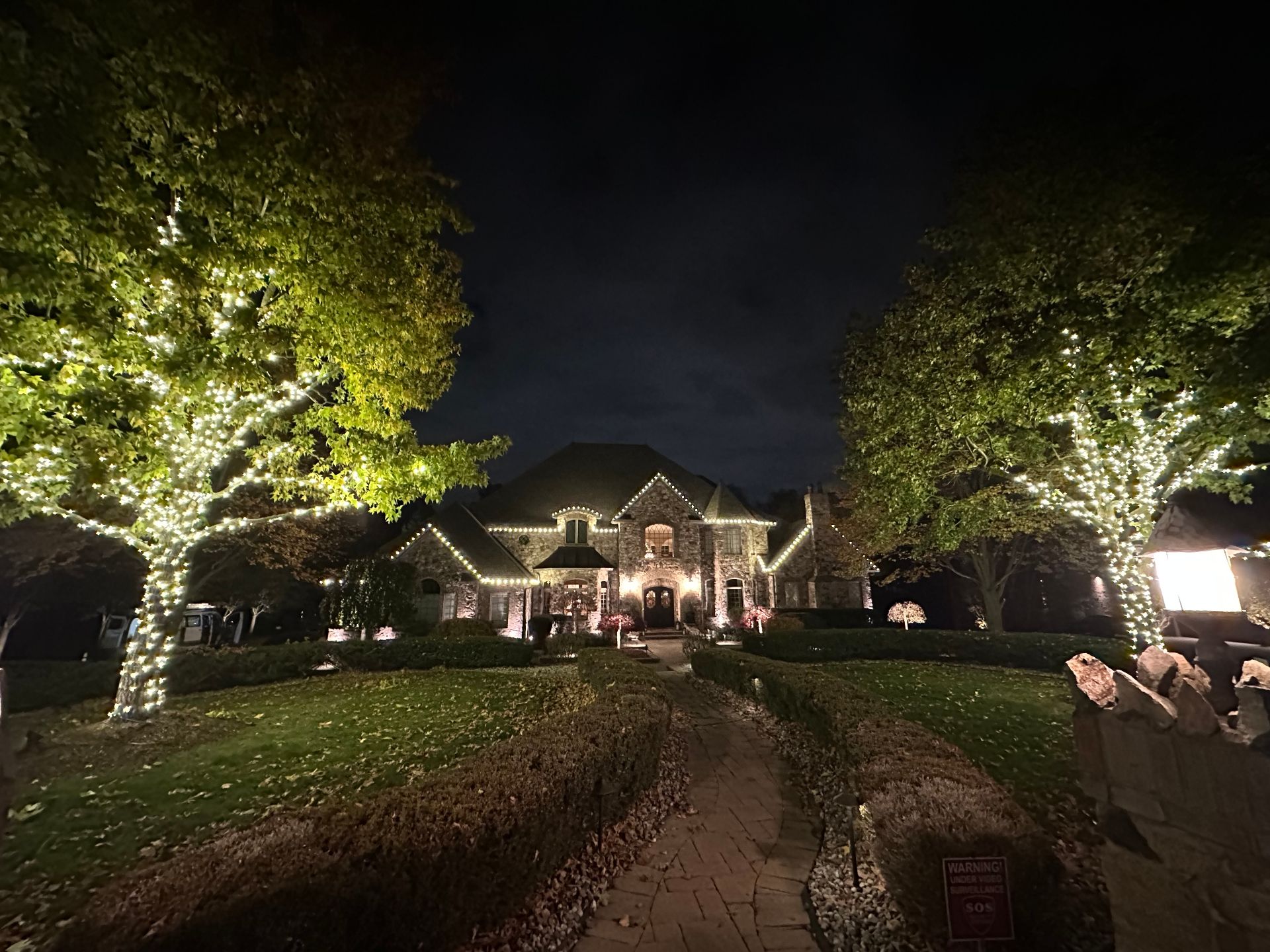 Estate with lit trees and roofline