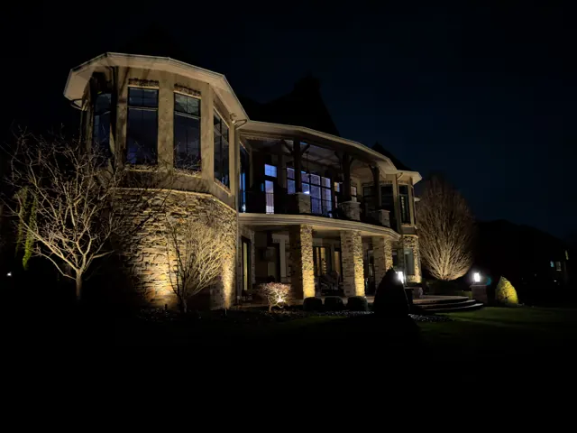 Stone home with a turret and balcony lit with architectural uplighting