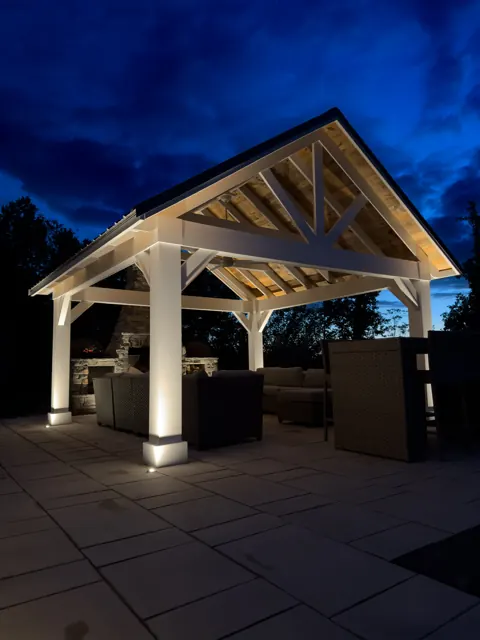 Timber-frame pavilion with lit columns at dusk