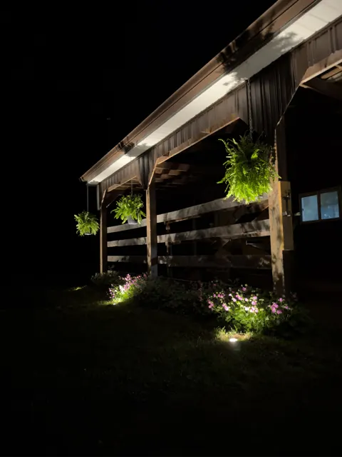 Porch roofline downlighting over lit flower beds