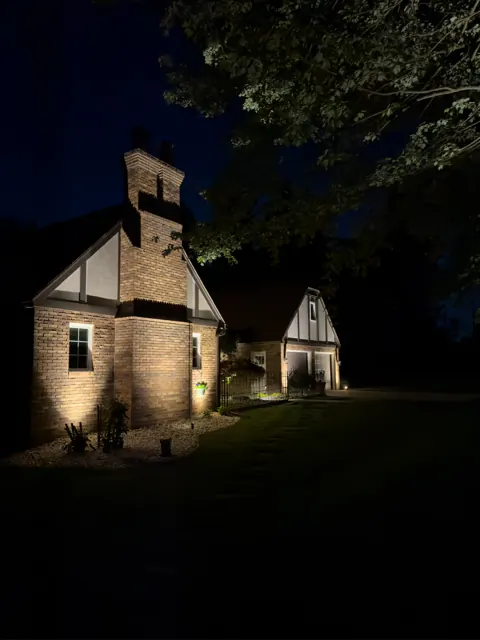 Tudor-style brick home with facade uplighting