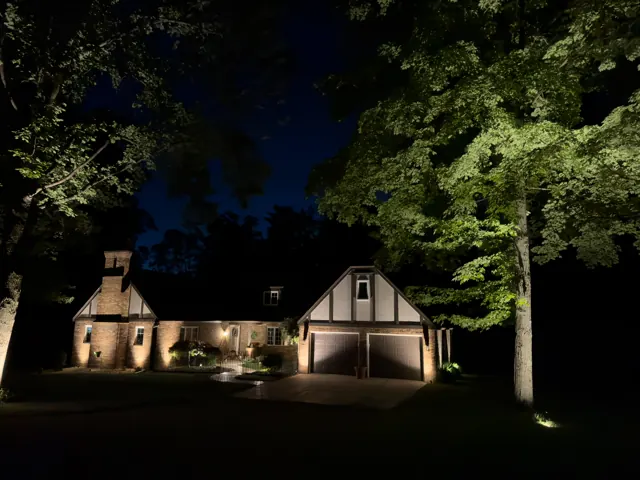 Tudor-style home and garage with tree lighting