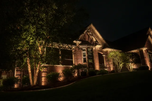 Brick ranch home with tree and facade lighting