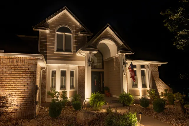 Two-story brick home with facade and entry lighting