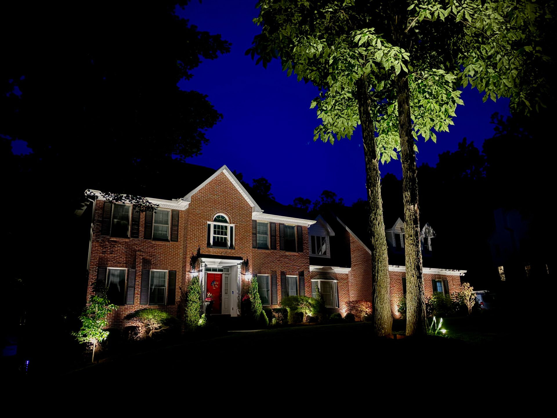 Colonial home with dramatic tree uplighting