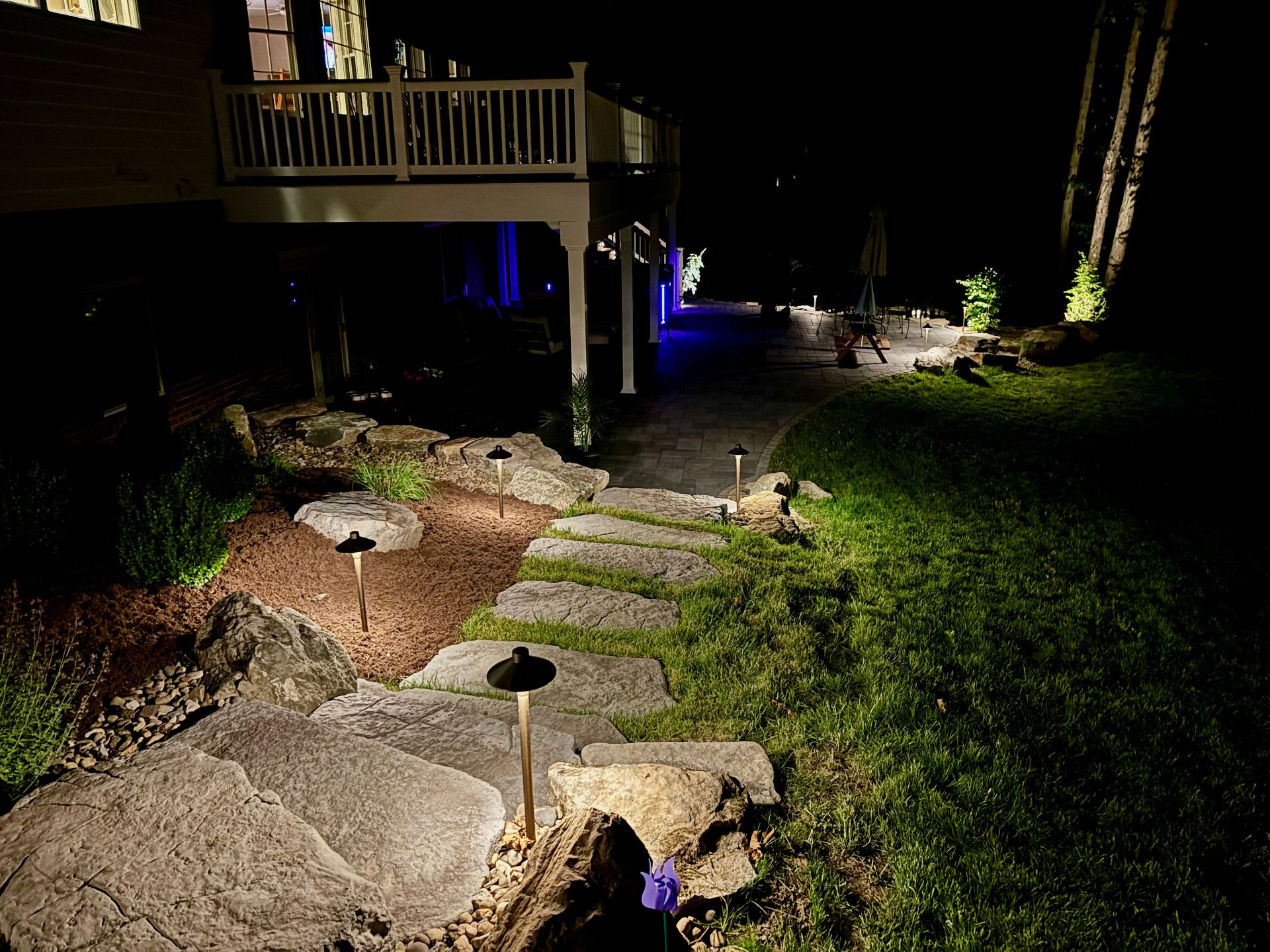 Backyard pathway with deck and accent lighting