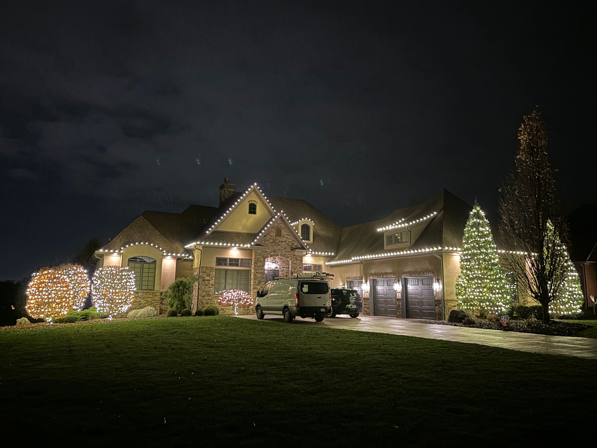 Stone estate with lit trees and shrubs