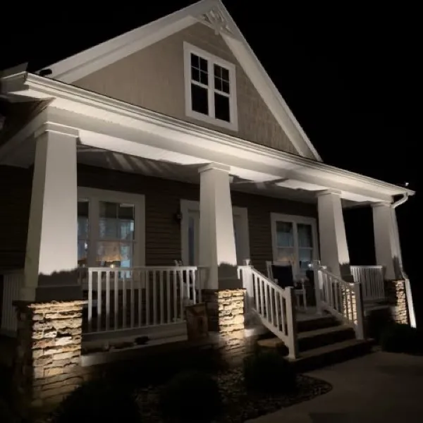White craftsman home with its porch and gable lit at night