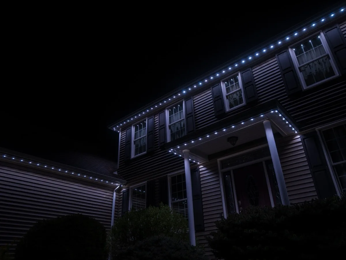 Permanent roofline lights on a two-storey home at full-brightness white for security lighting